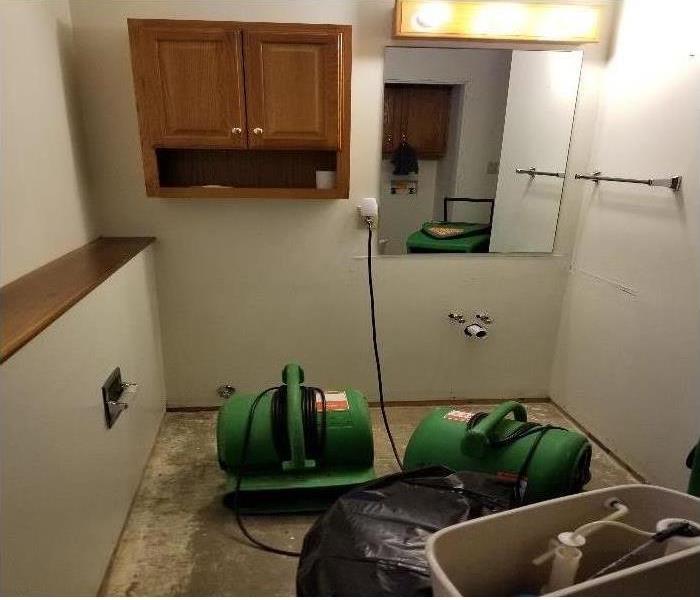 Green air movers in place drying out water damaged bathroom