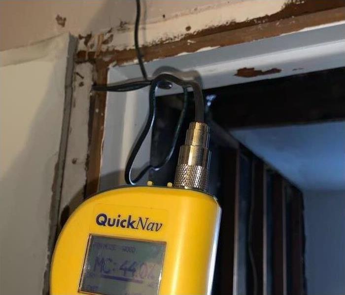Moisture Meter Reading moisture level on home with cracked paint and drywall