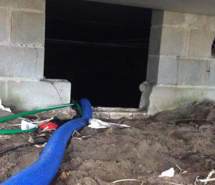 A home crawlspace with dust and debris present. A water extractor is in place. 