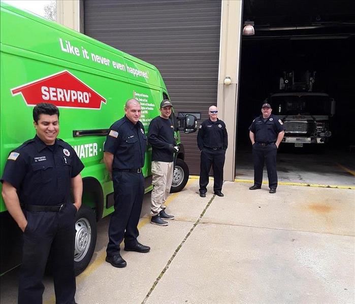Men lined up in front of a green SERVPRO van. 