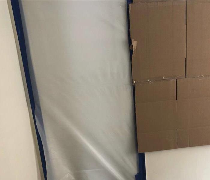 plastic sheet over doorway and cardboard on the wall. 